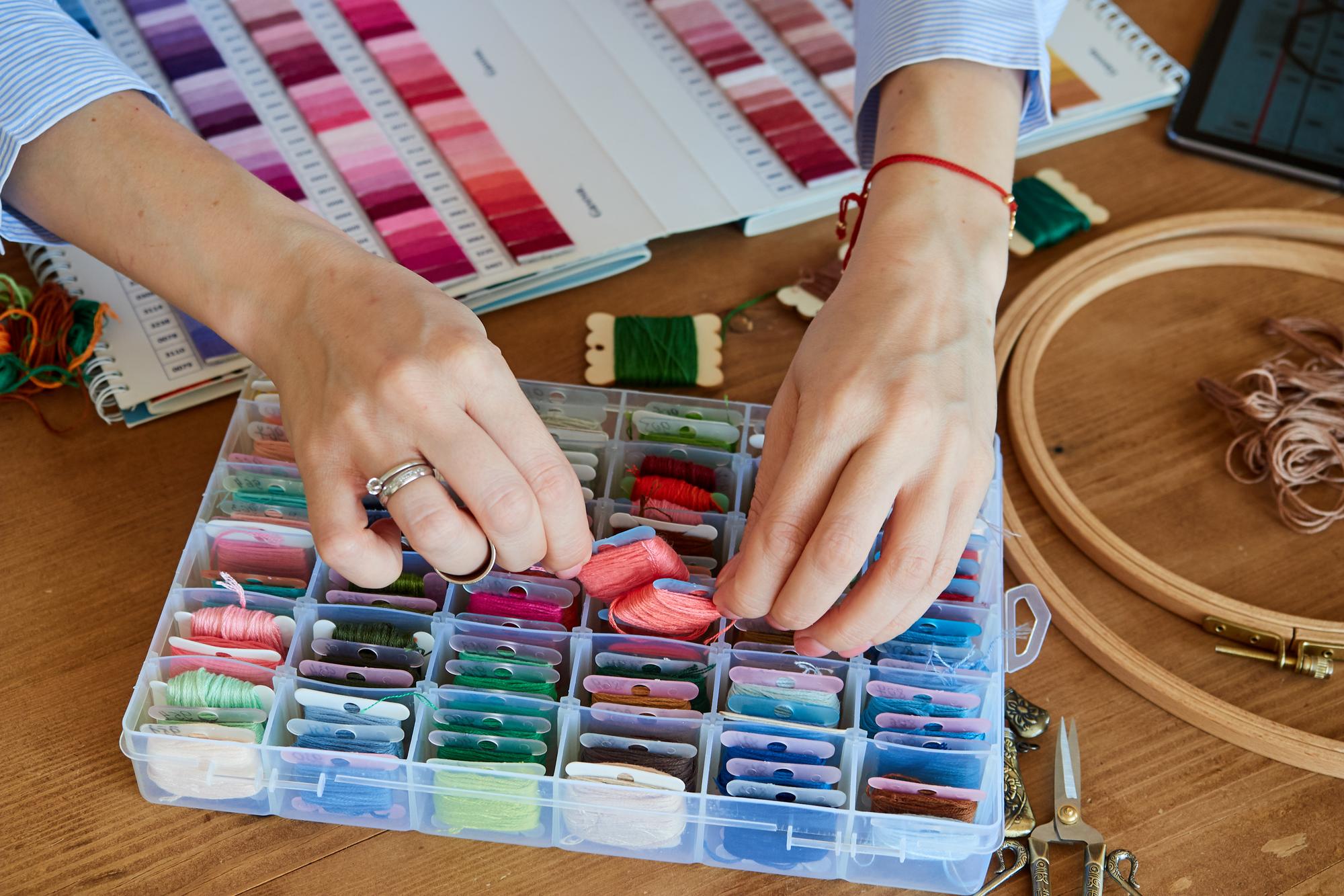 hands arranging embroidered samples on table